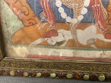 A Tibetan thangka in inlaid gilt brass frame, 19th C.